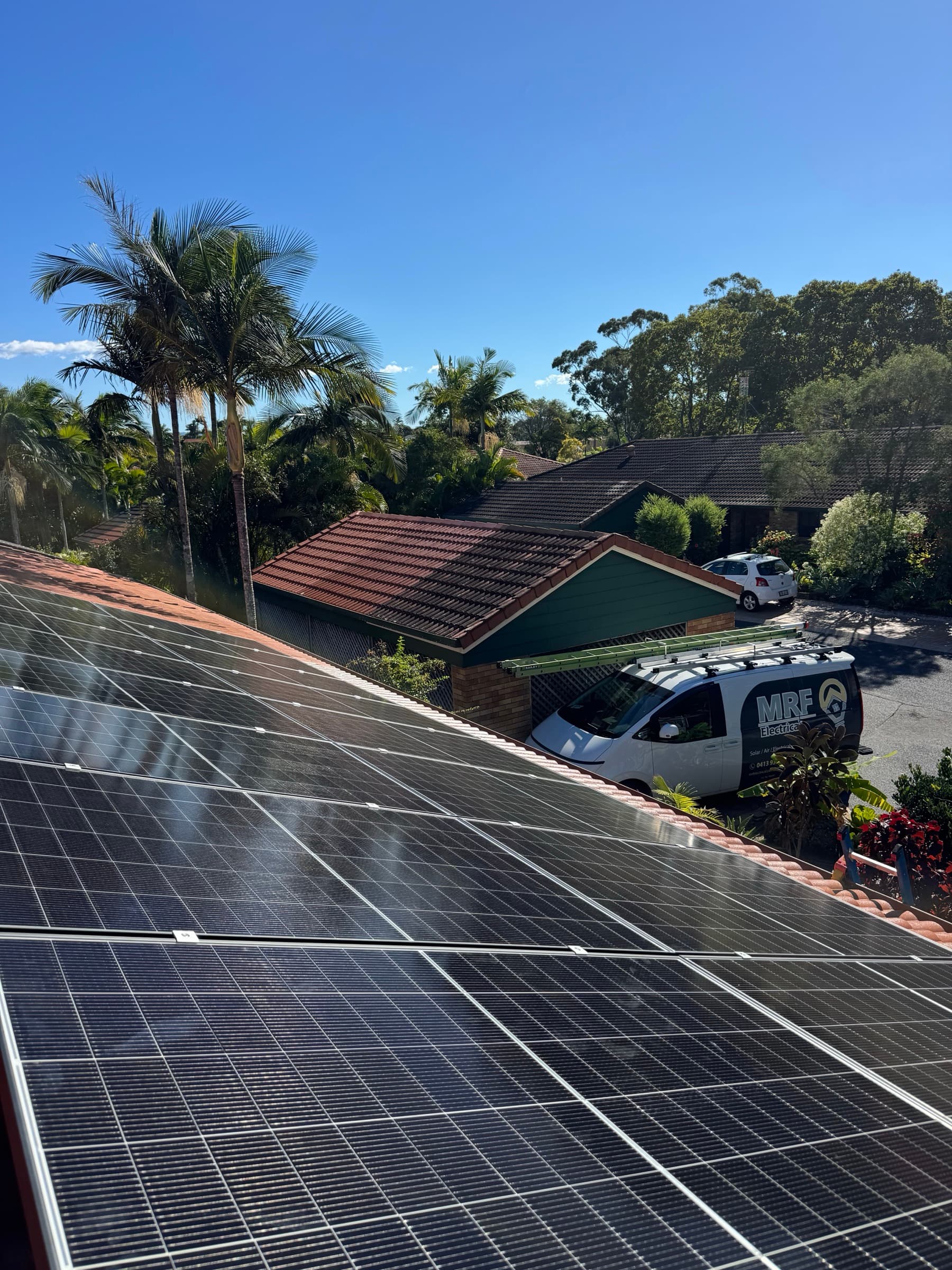 Rooftop solar panel installation with the MRF Electrical van parked on a northside Brisbane street below
