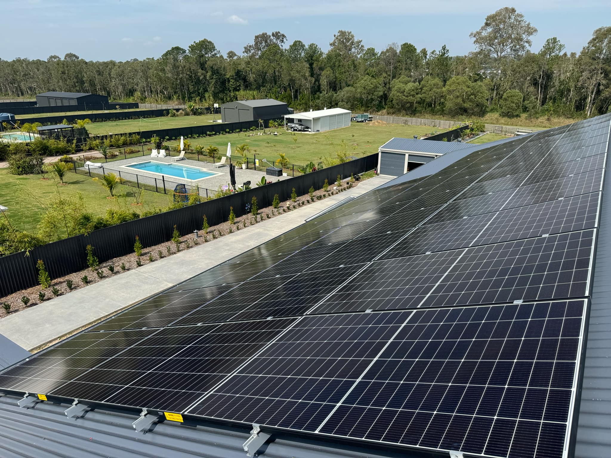 Aerial view of a completed rooftop solar installation on a home with a pool