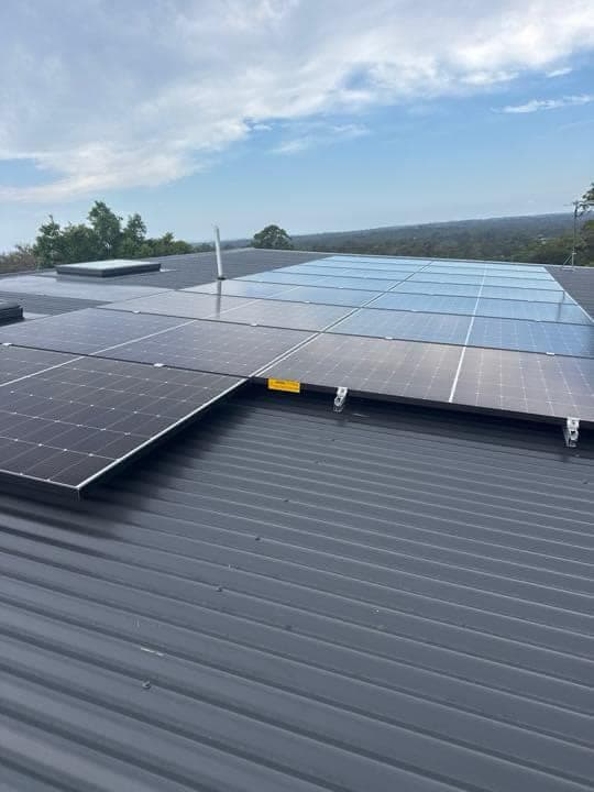 Rooftop solar panels installed with a coastal view in the background