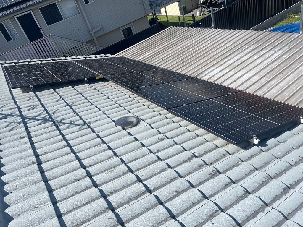Rooftop solar panel installation with an MRF Electrical service vehicle parked below