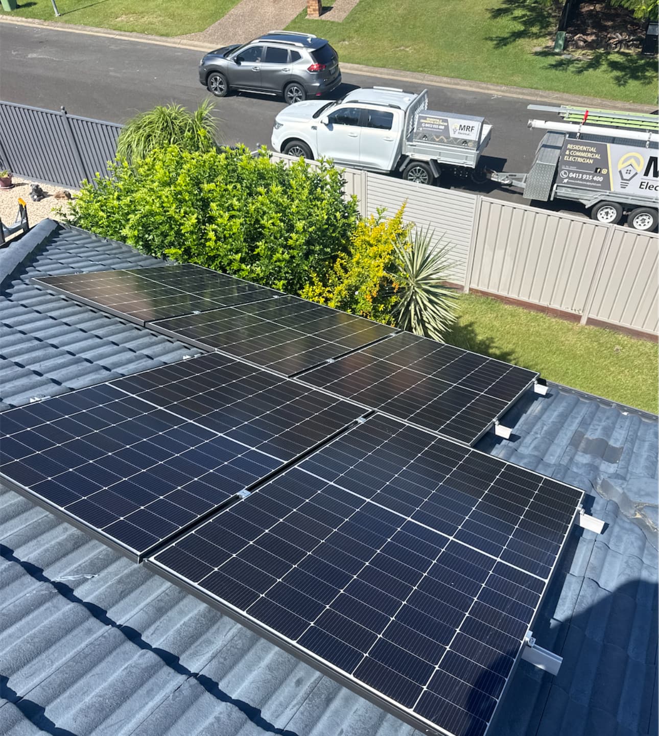 MRF Electrical technician and service vehicle beside a completed rooftop solar installation, northside Brisbane